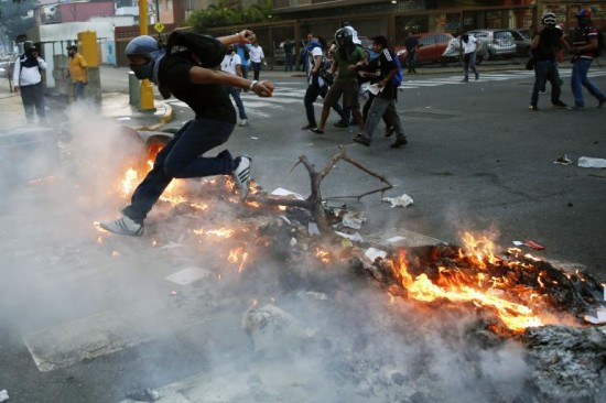 Un partidario del líder opositor Leopoldo López salta por encima de una barricada ardiendo durante una protesta contra el gobierno de Nicolás Maduro, en Caracas, 19 de febrero 2014. Las tensiones han aumentado en Venezuela desde que López, un economista educado en Harvard de 42 años de edad, se entregó a las tropas el martes después de encabezar tres semanas de manifestaciones a menudo escandalosos contra el gobierno del presidente Nicolas Maduro. REUTERS / Carlos Garcia Rawlin